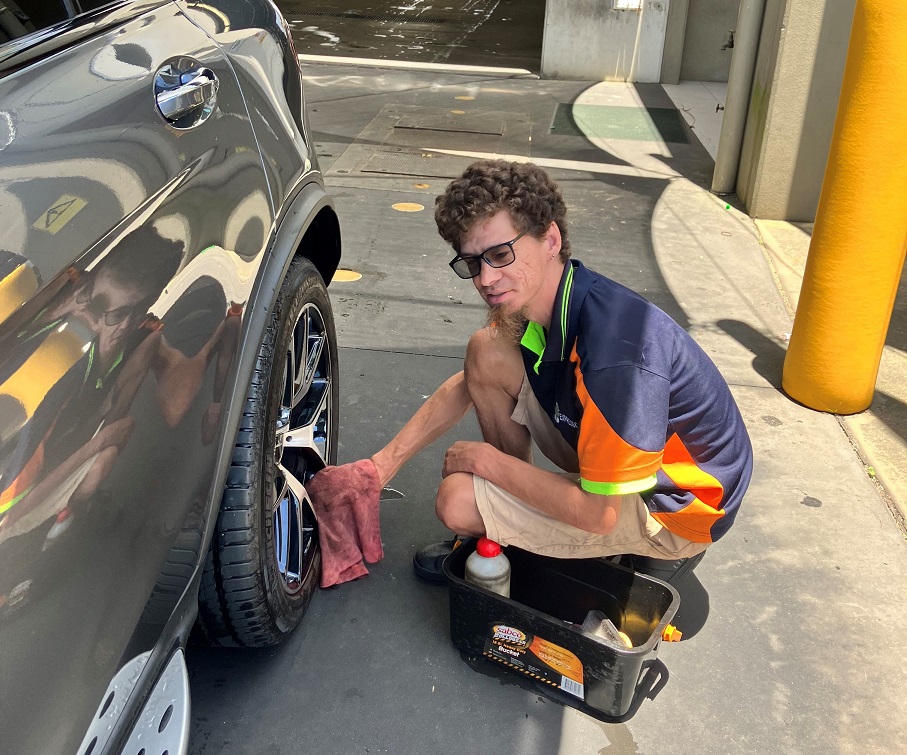 Doug, tradie cleaning car tyre.