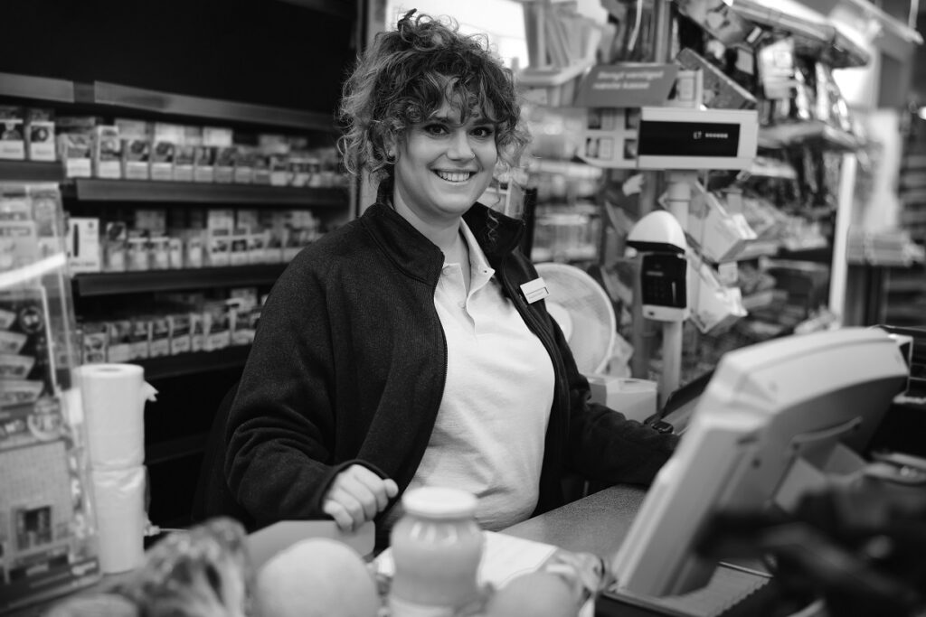 Woman cashier at supermarket. Cash register clerk smiling at camera.